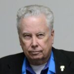 A man with white hair and wearing a blue shirt.